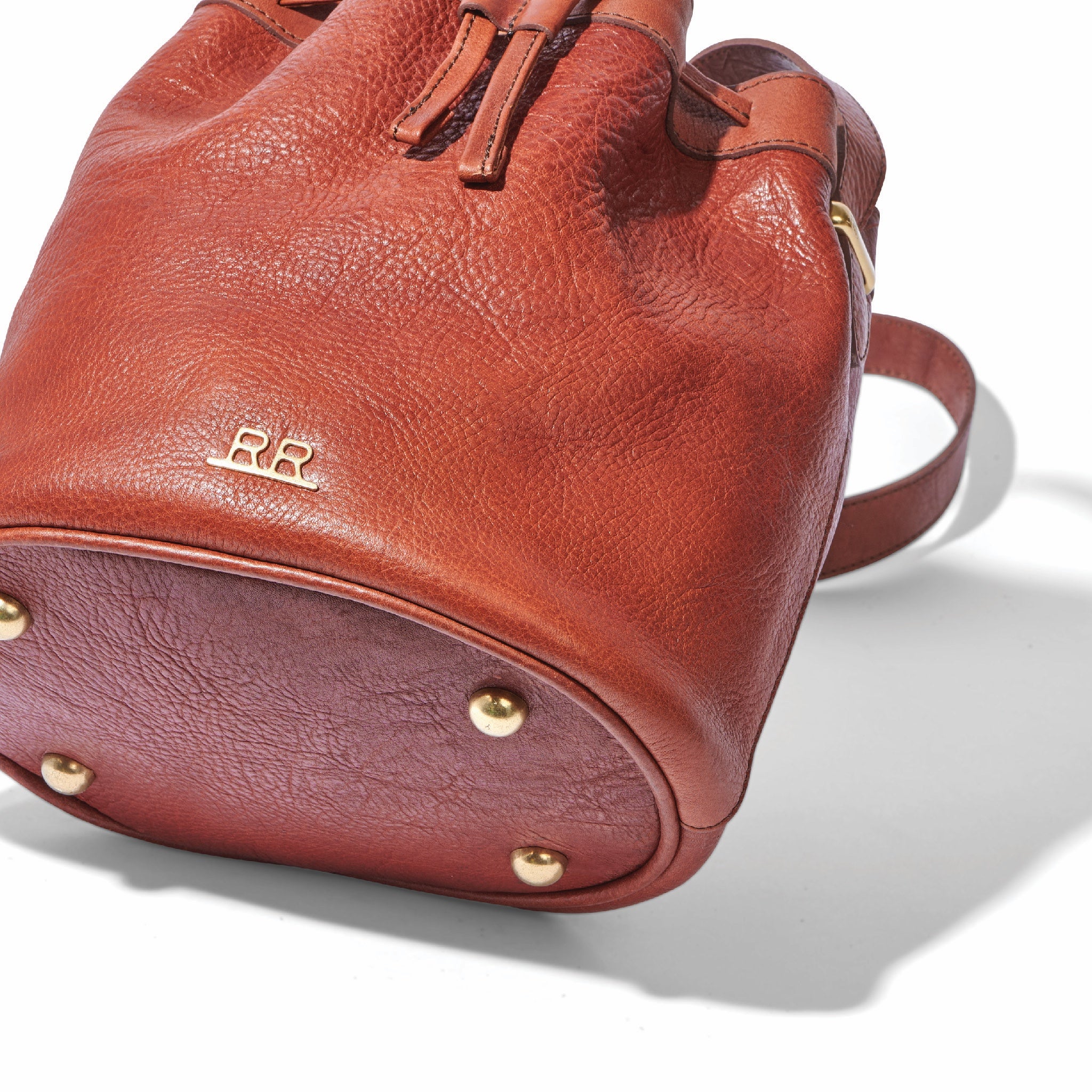 Regenerative leather crossbody bucket bag with brass feet and soft structure