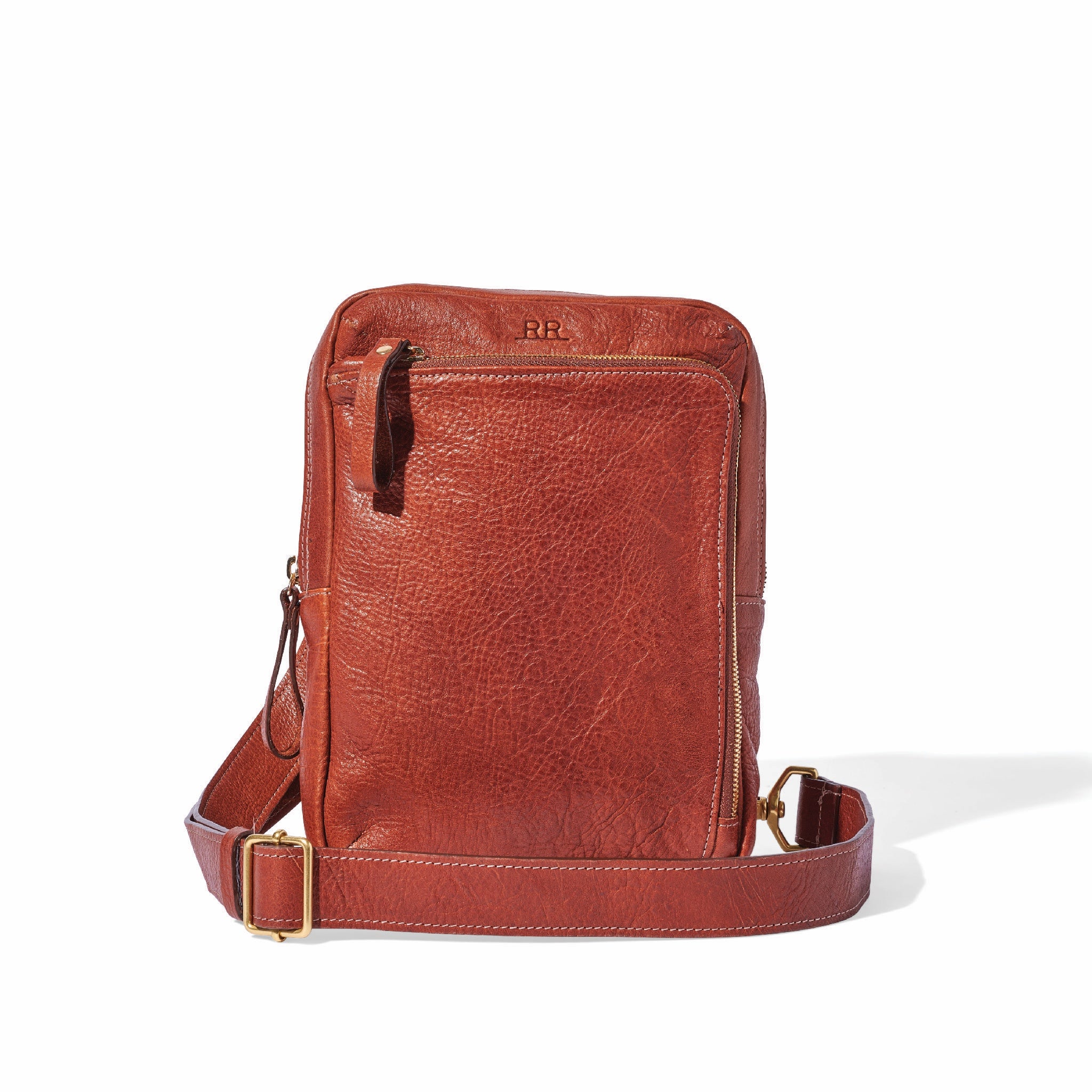 Sling Bag in Mahogany brown leather worn crossbody with zip compartment and brass accents